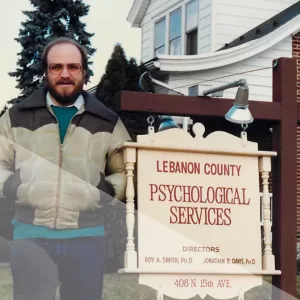 Roy with sign at original PaCounseling location in 1980's