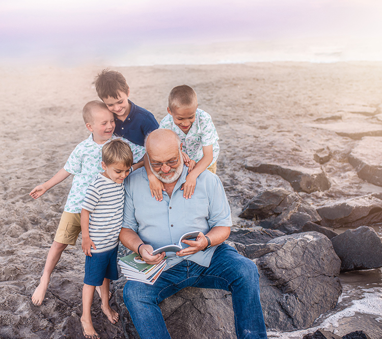 Dr. Roy Smith with his grandchildren at the beach reading "The Campfire Gang".